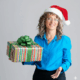L'autrice souriante, porte un chapeau de Noël. Elle présente un cadeau coloré.